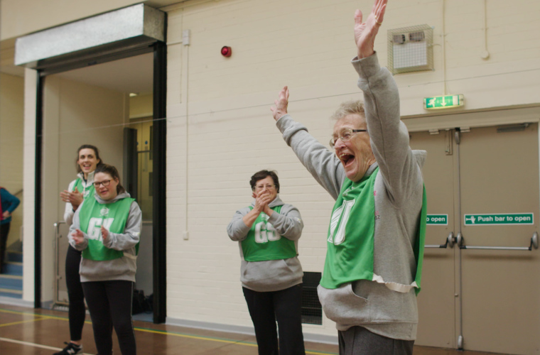 Older woman celebrates scoring a goal in game of netball