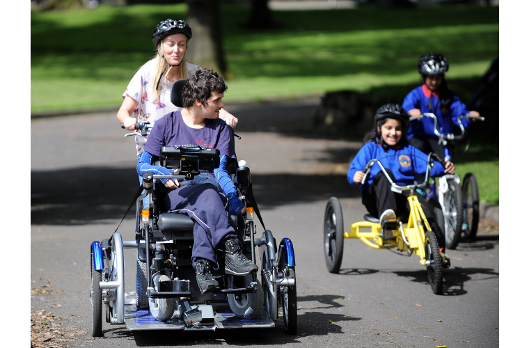 Young disabled people taking part in an adapted cycling session in the park