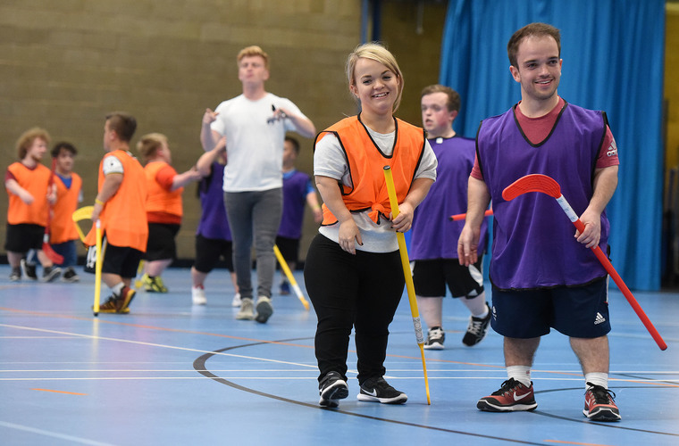 Two young adults with dwarfism playing indoor hockey