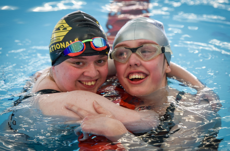 Two swimmers hugging at the end of a race in pool