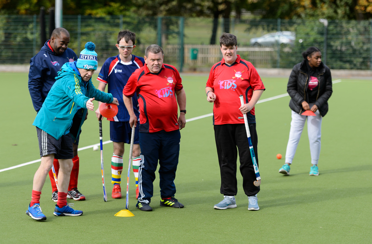 Hockey coach demonstrating a drill to players during a training session. Photo credit: Sport England 