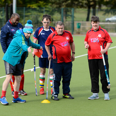 Hockey coach demonstrating a drill to players during a training session. Photo credit: Sport England