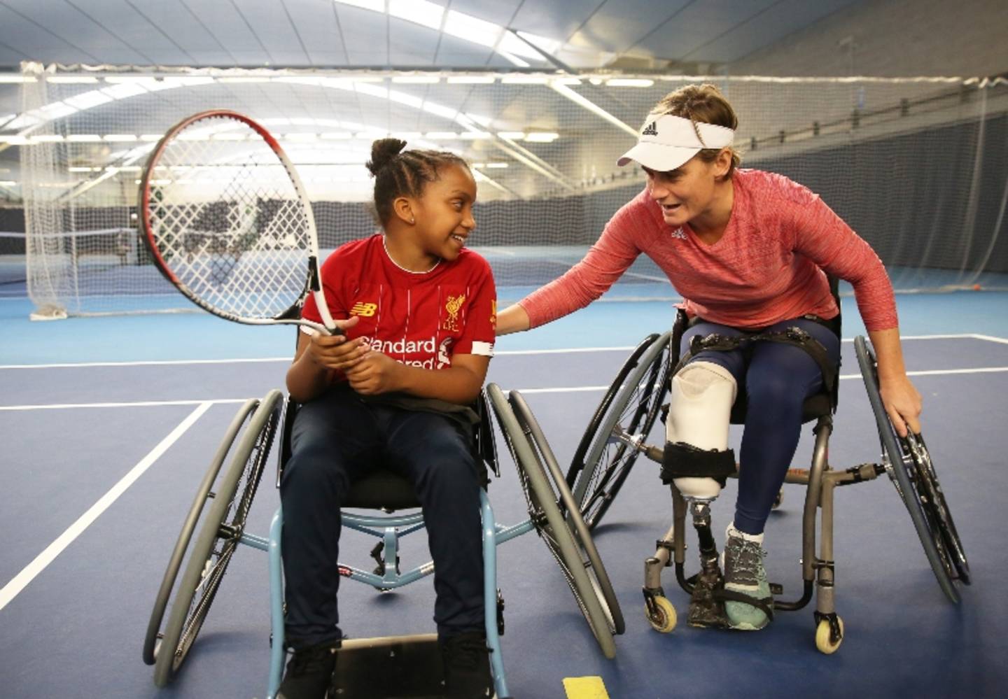 Young girl trying out wheelchair tennis with tennis coach