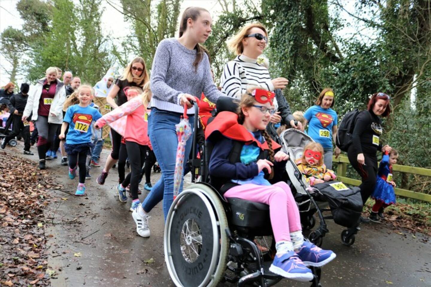 Families with disabled children taking part in a charity walking event in a park.