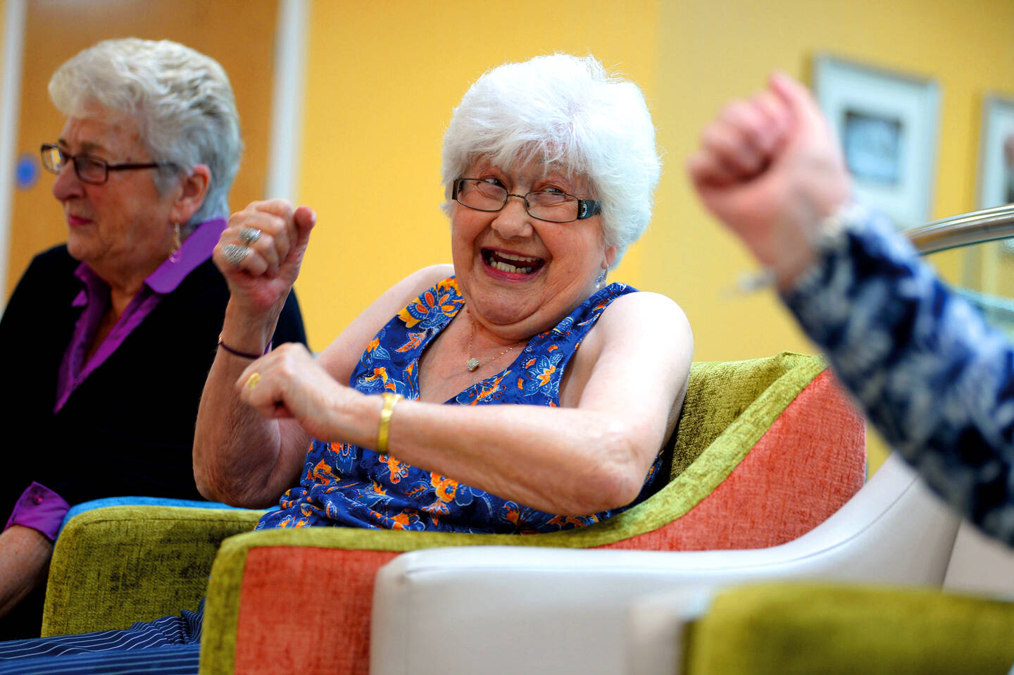 A group of older people taking part in seated dancing.