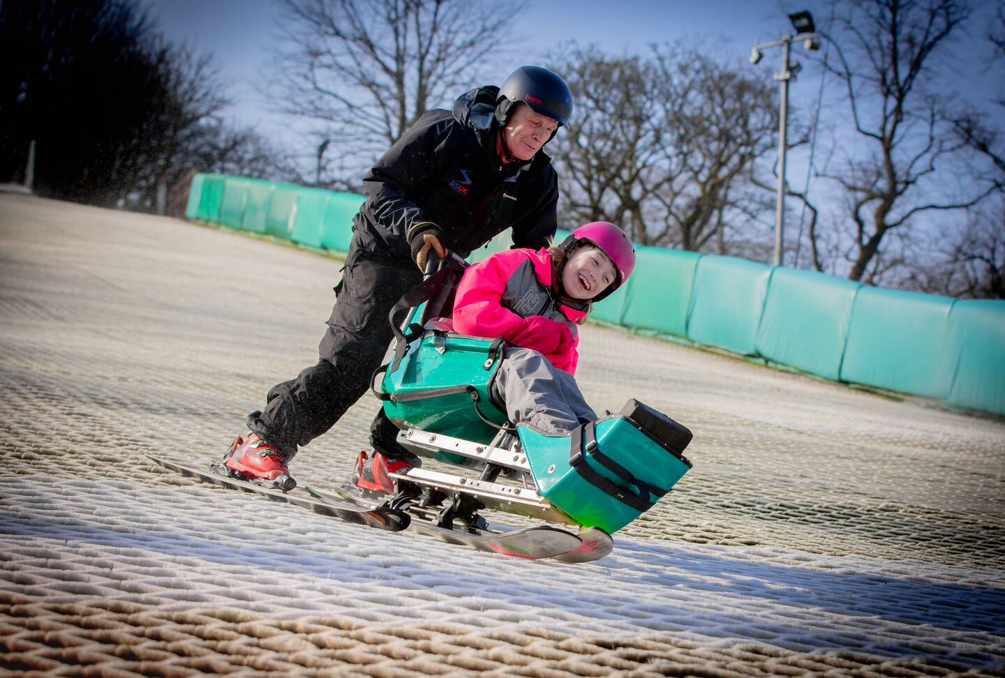 Disability SnowSport UK man pushing young woman on ski