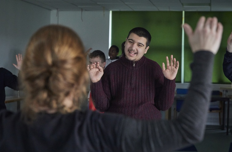 Young disabled man smiling at yoga instructor while taking part in the yoga class 