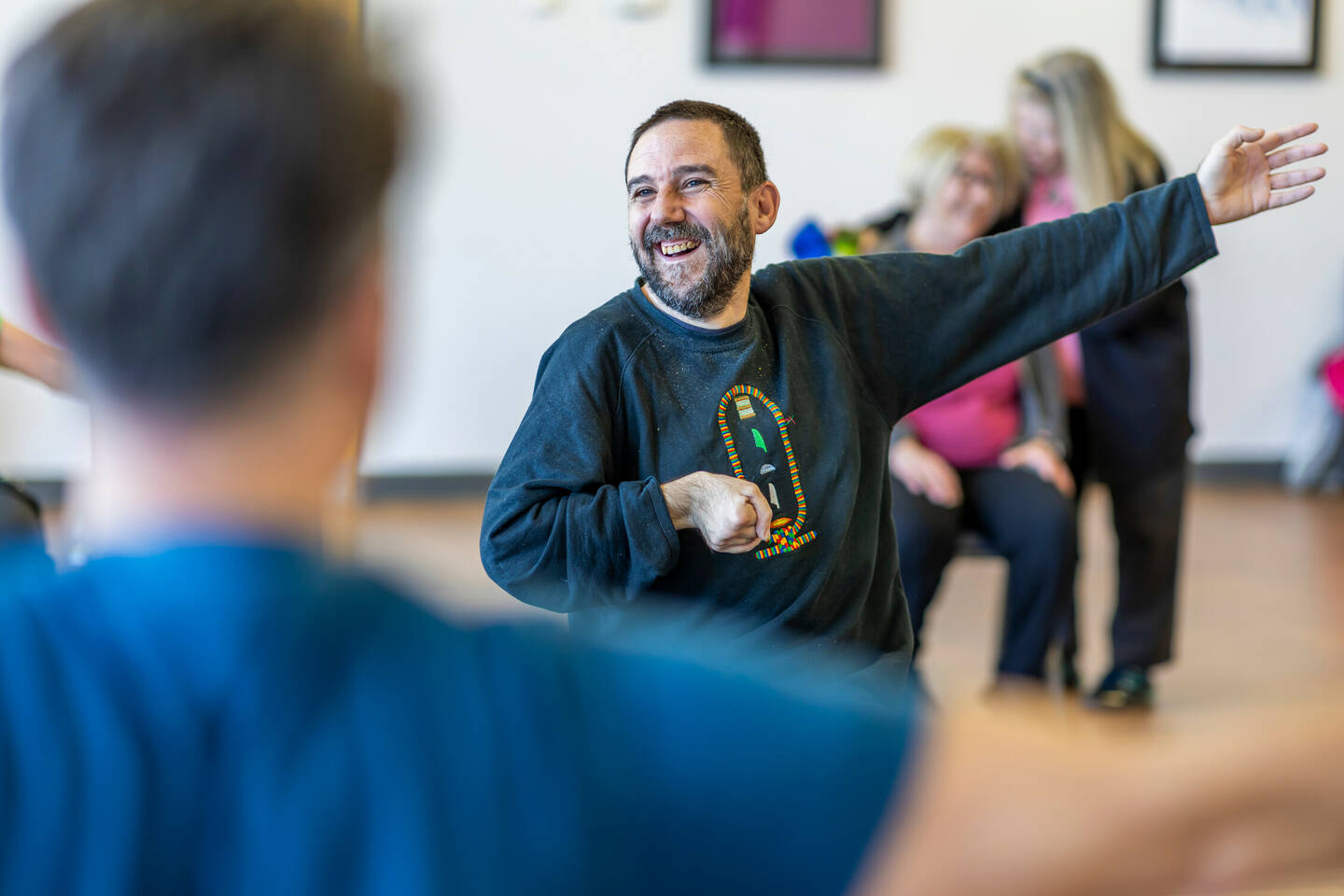 Older disabled man smiling as he takes part in seated exercise class