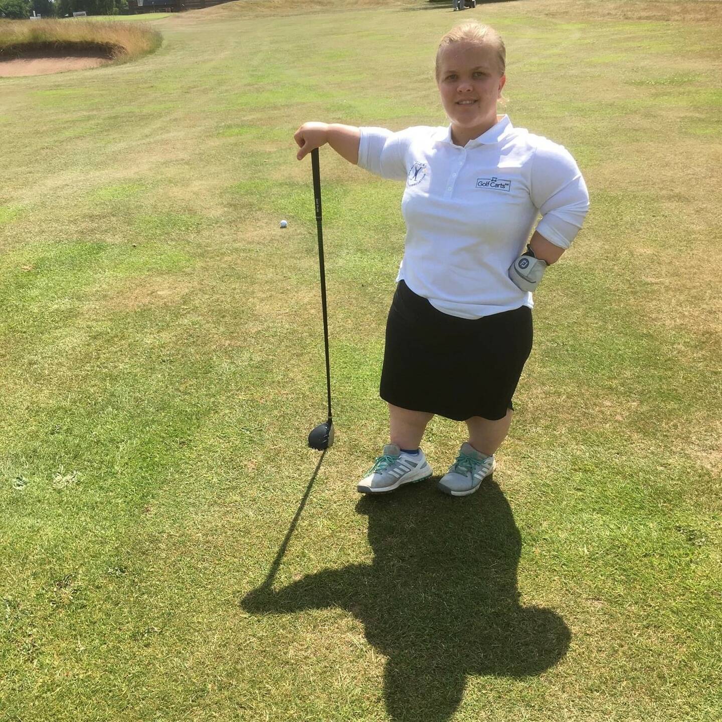 Ellie on golf course with club in hand smiling to camera