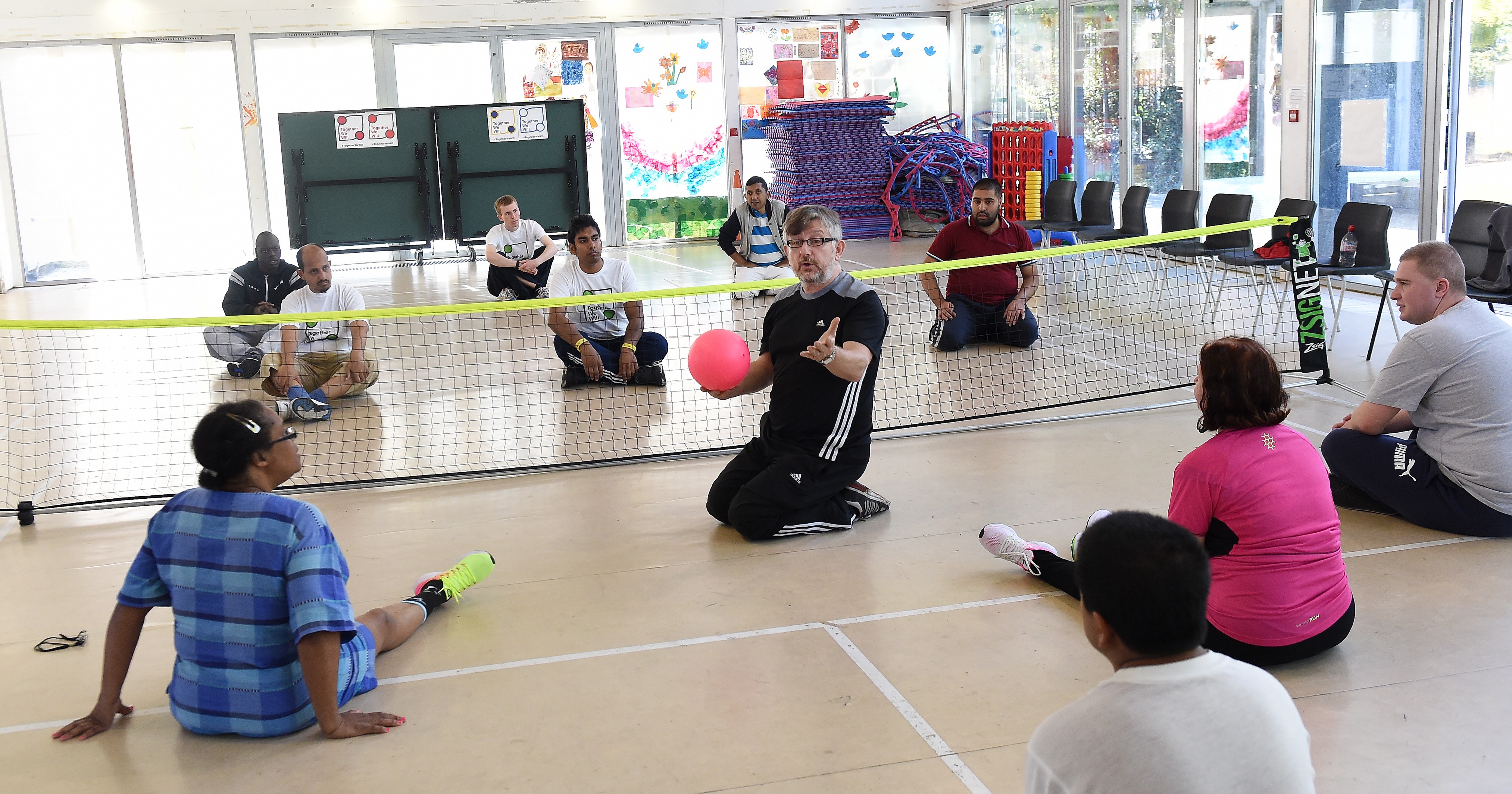 Group of disabled and non-disabled people playing sitting volleyball