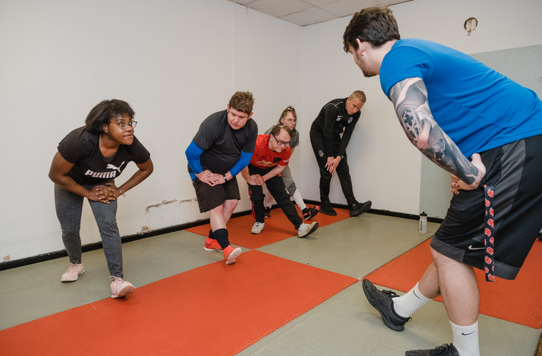 Group of disabled people doing leg stretches during a group PT session