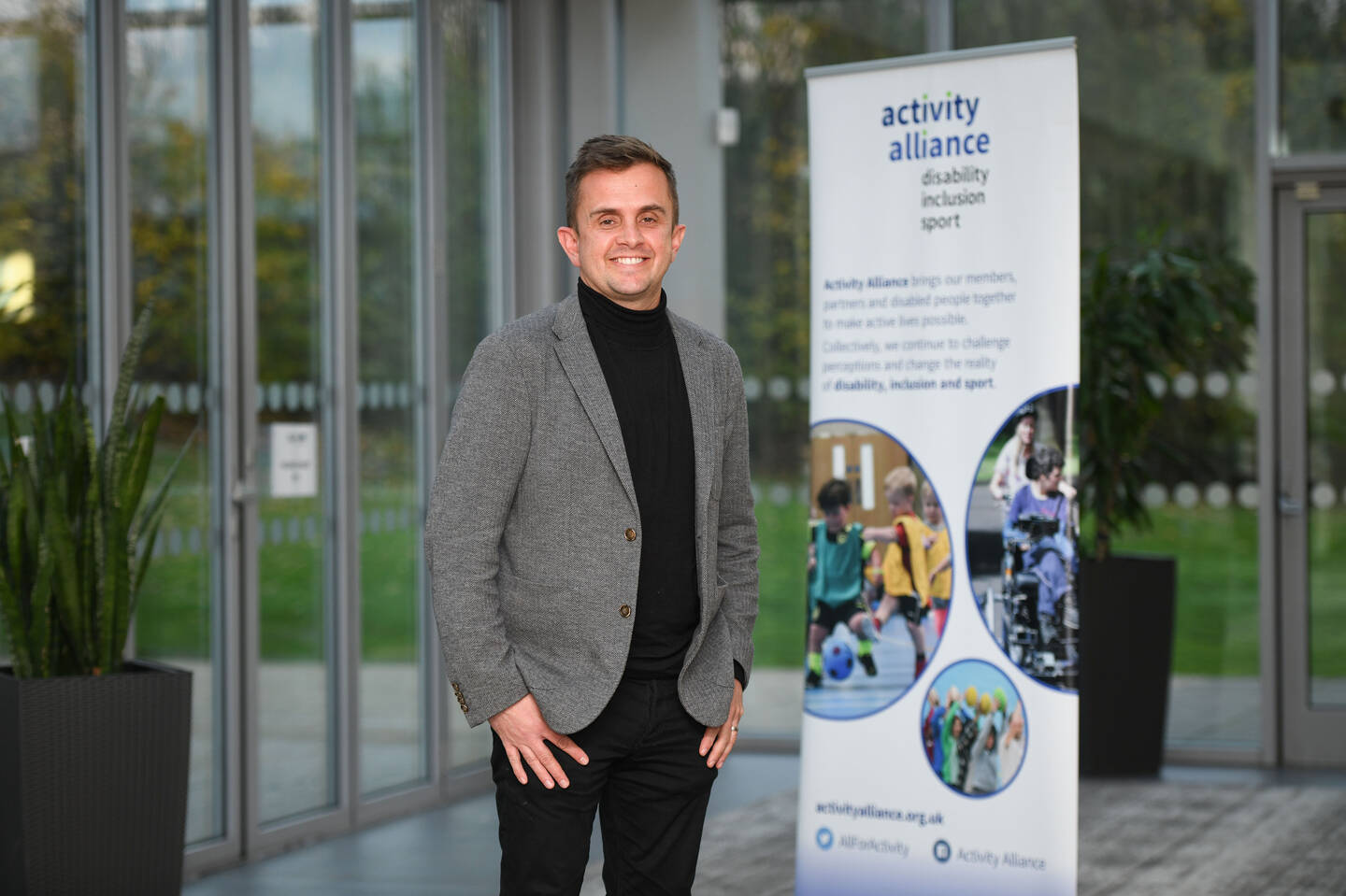 Adam Blaze CEO standing in front of an Activity Alliance pop up banner