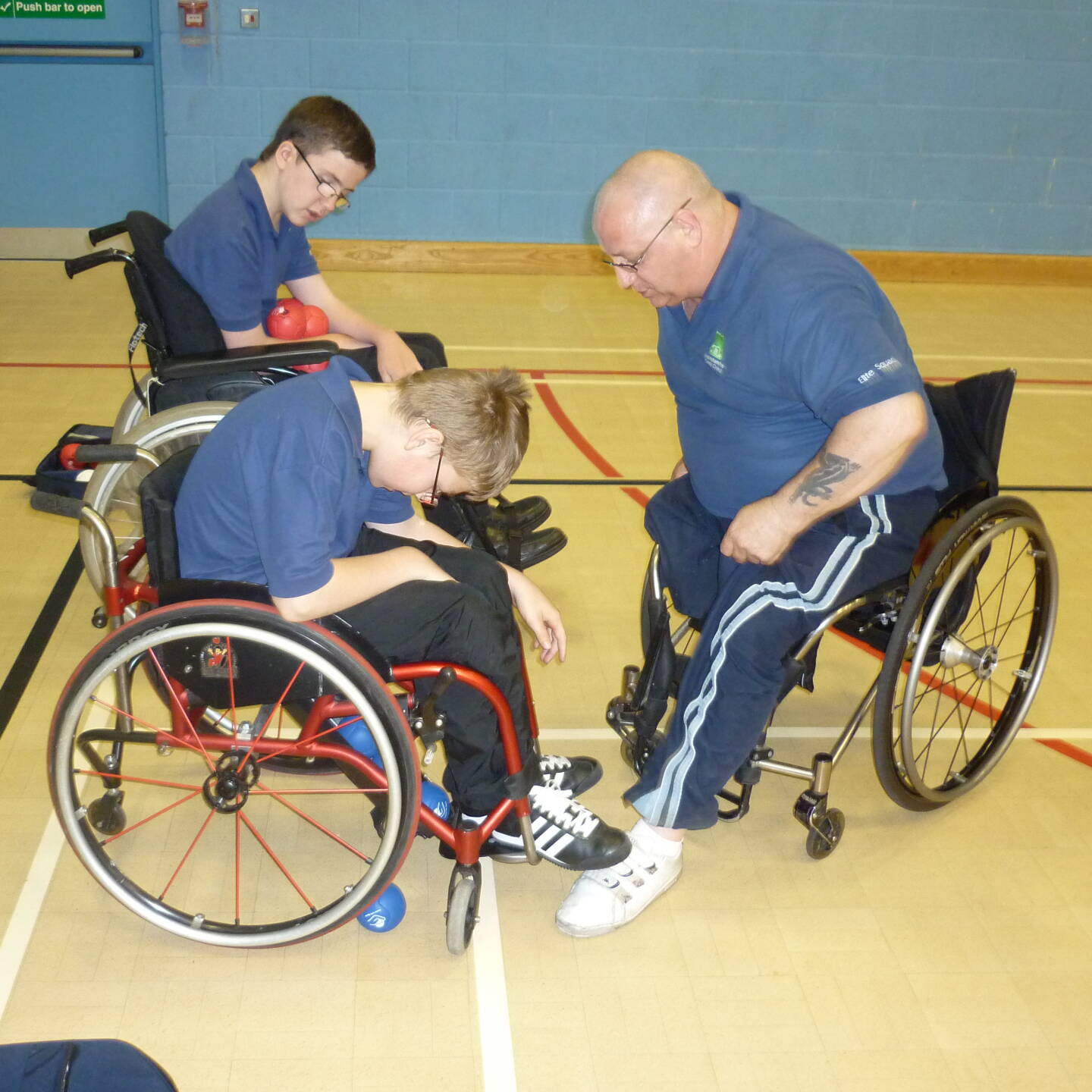 Pete Edwards coaching Boccia to two young boys.  