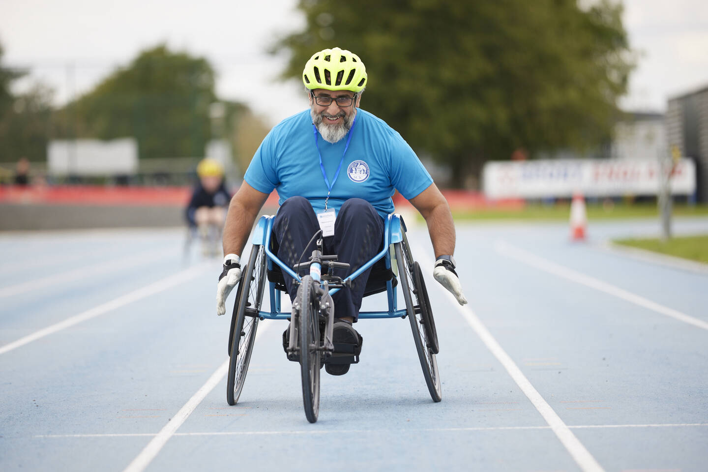A man with a beard in a wheelchair racer on a track.