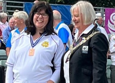 Elaine stand next to another woman in a blazer with a bronze medal around her neck .