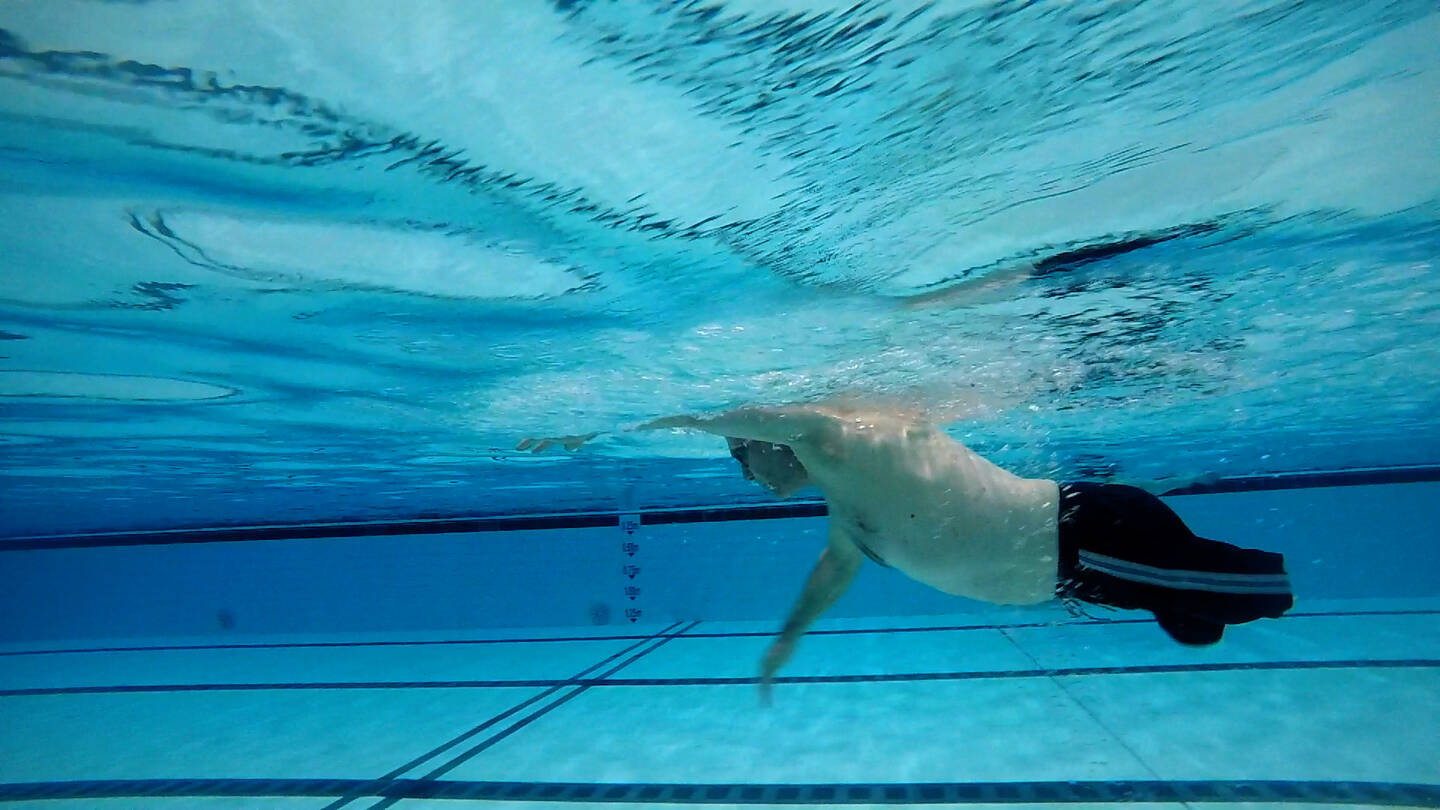 Man with lower limb impairments swimming under the surface of the water.