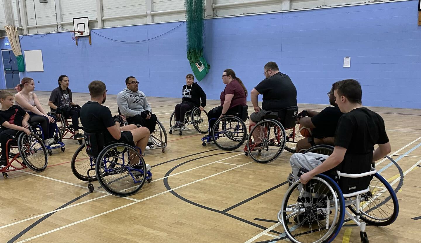 A group of wheelchair users in a sports hall.