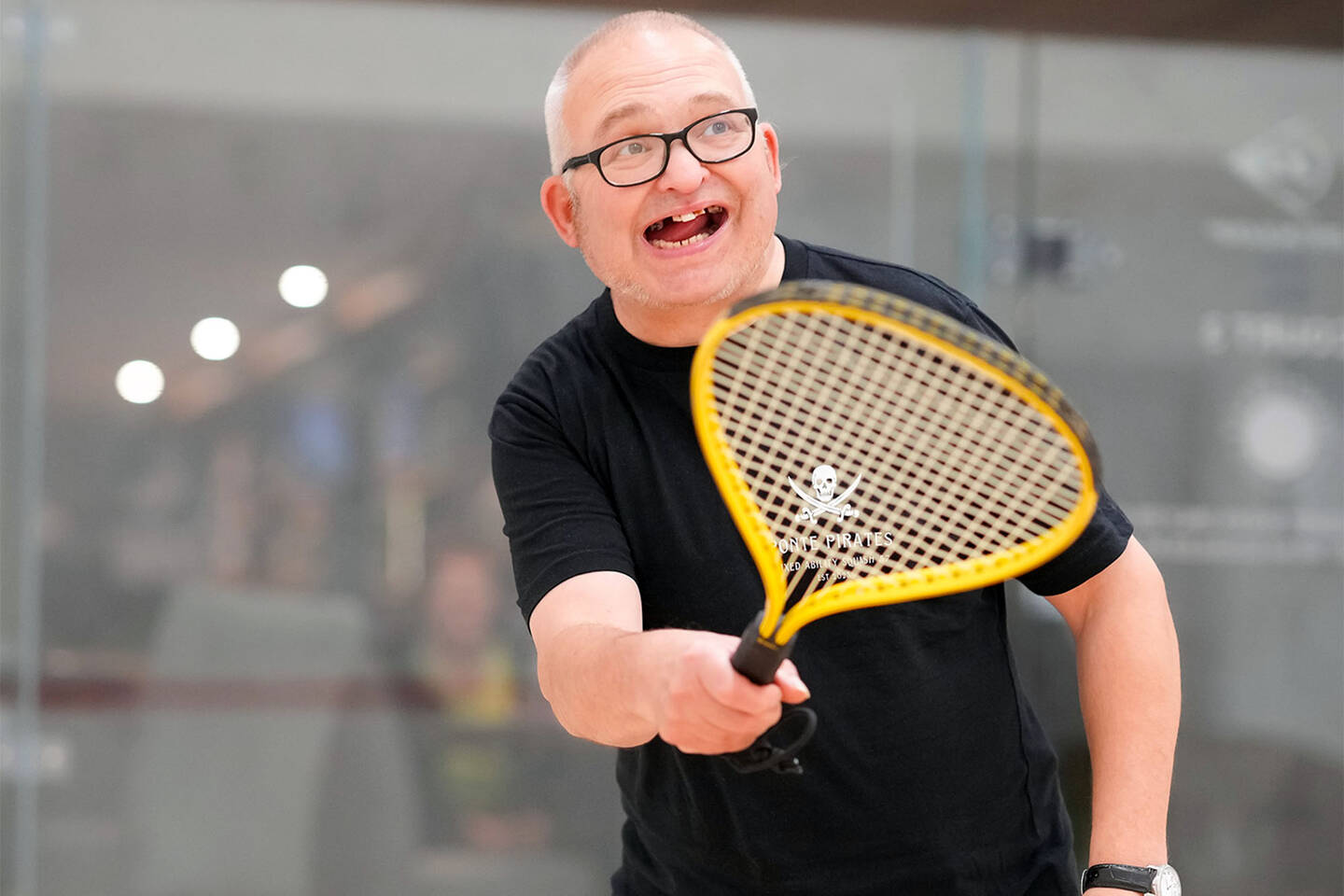 A man playing squash with a yellow racket.