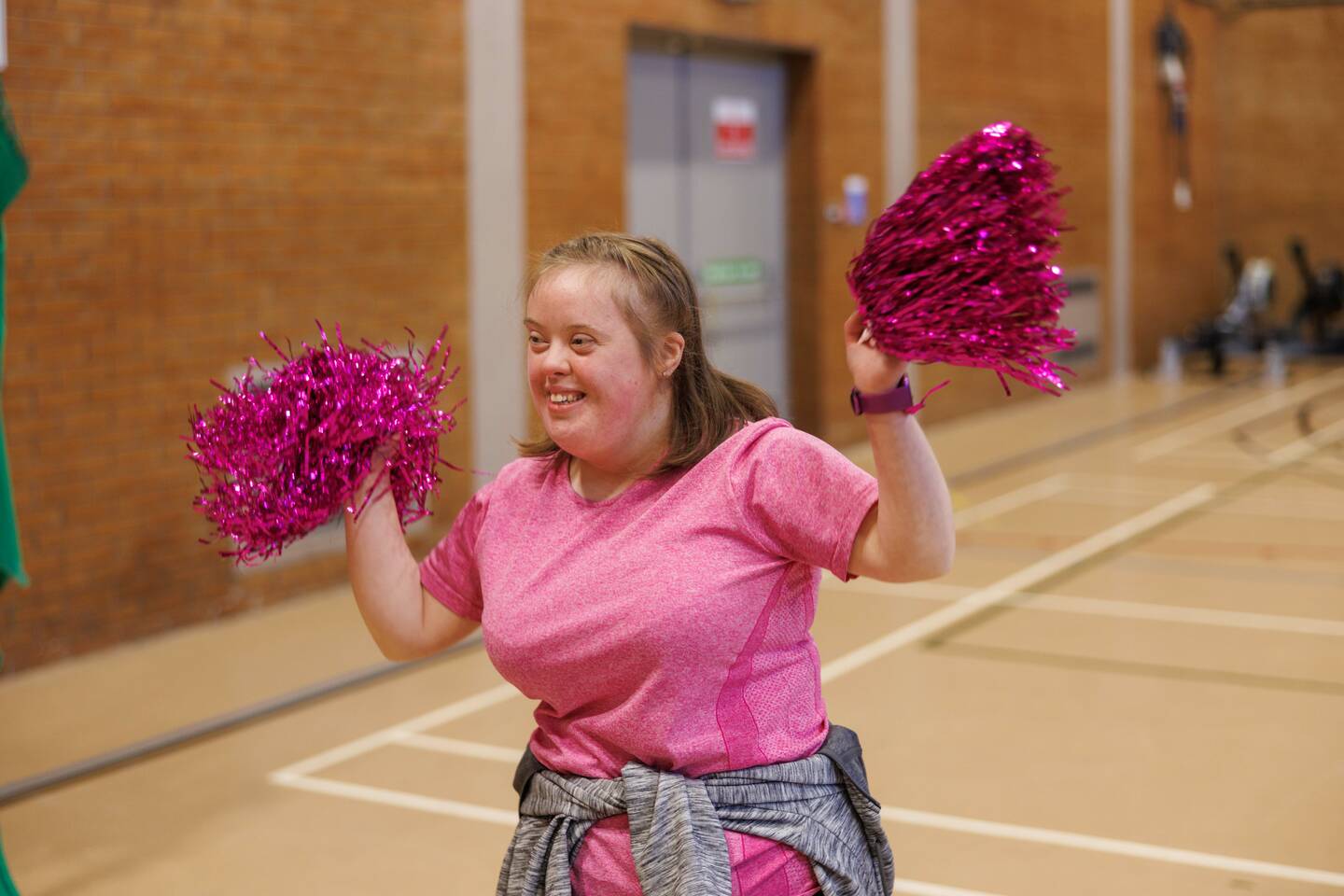Giel dancing with pom poms in a sports hall. 