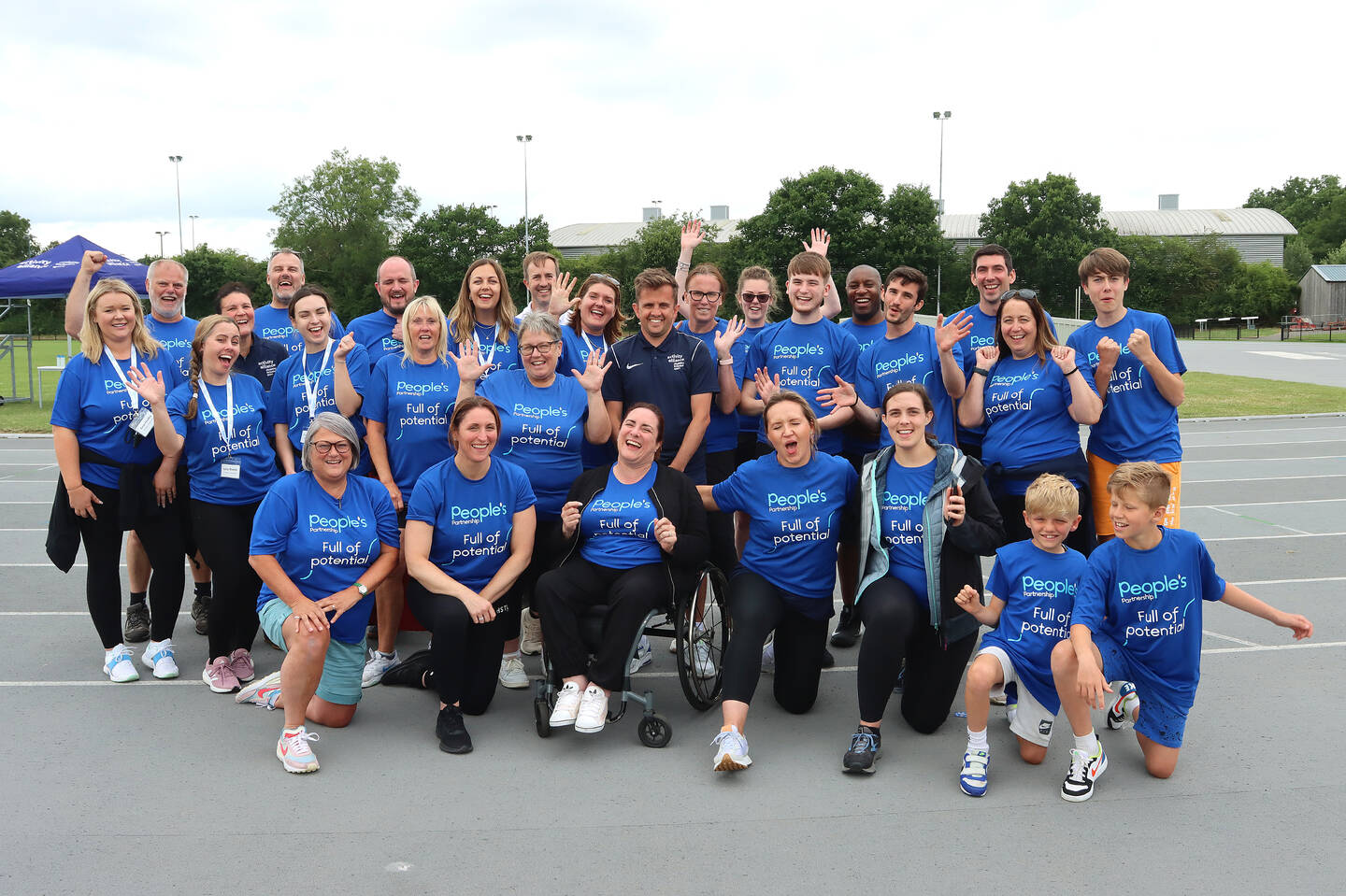 A group of people pose on an athletics track. 