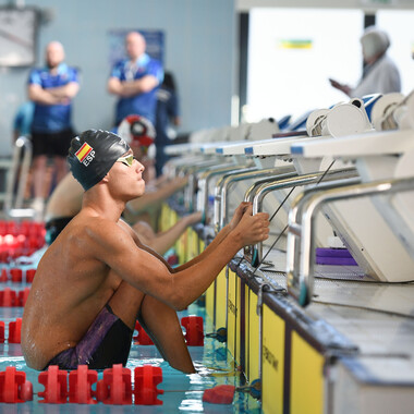 A man in a Spanish swimming cap ready to start a backstroke race in the pool.