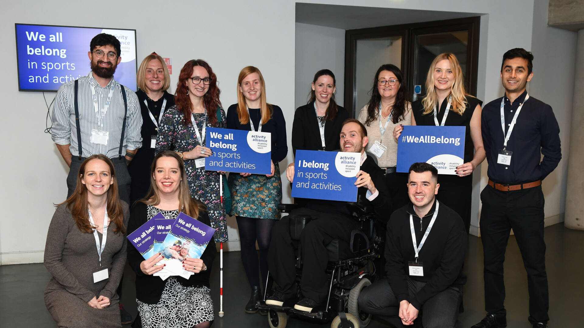 A group of Activity Alliance staff hold up placards.