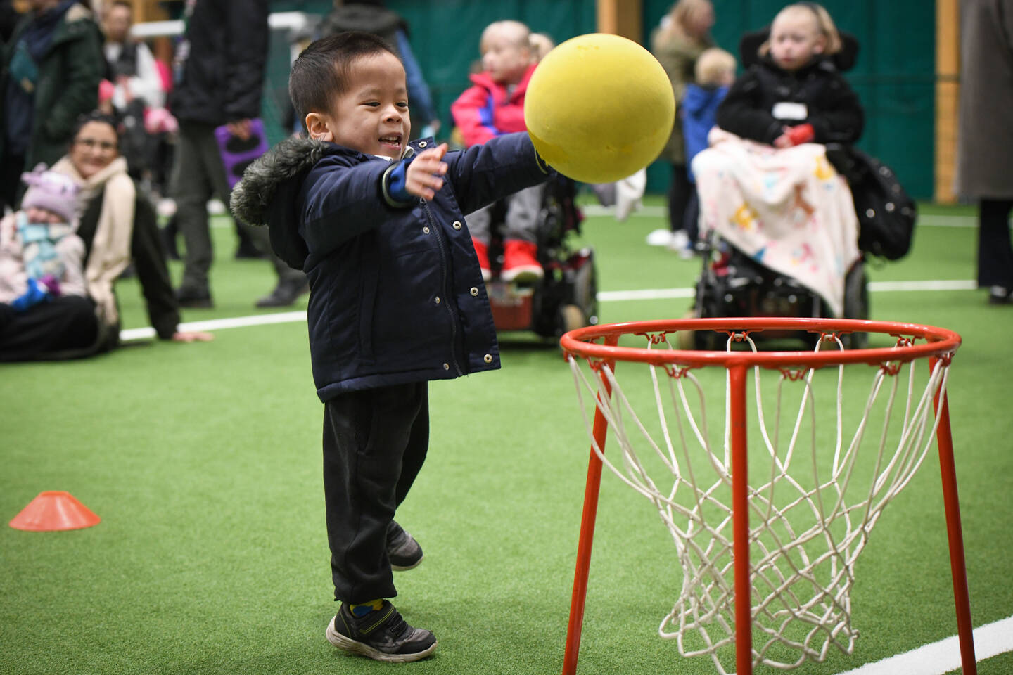 A boy in a coat throws a ball into a net.