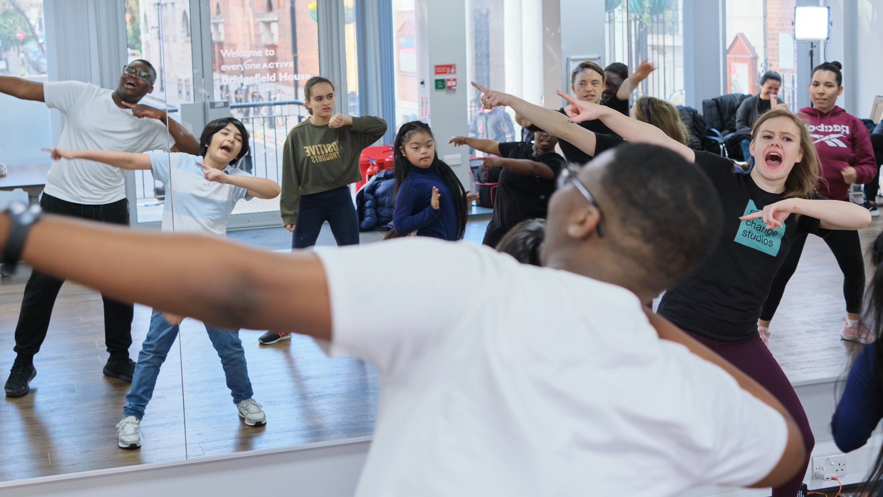 A group put their hands in the air in a dance class.