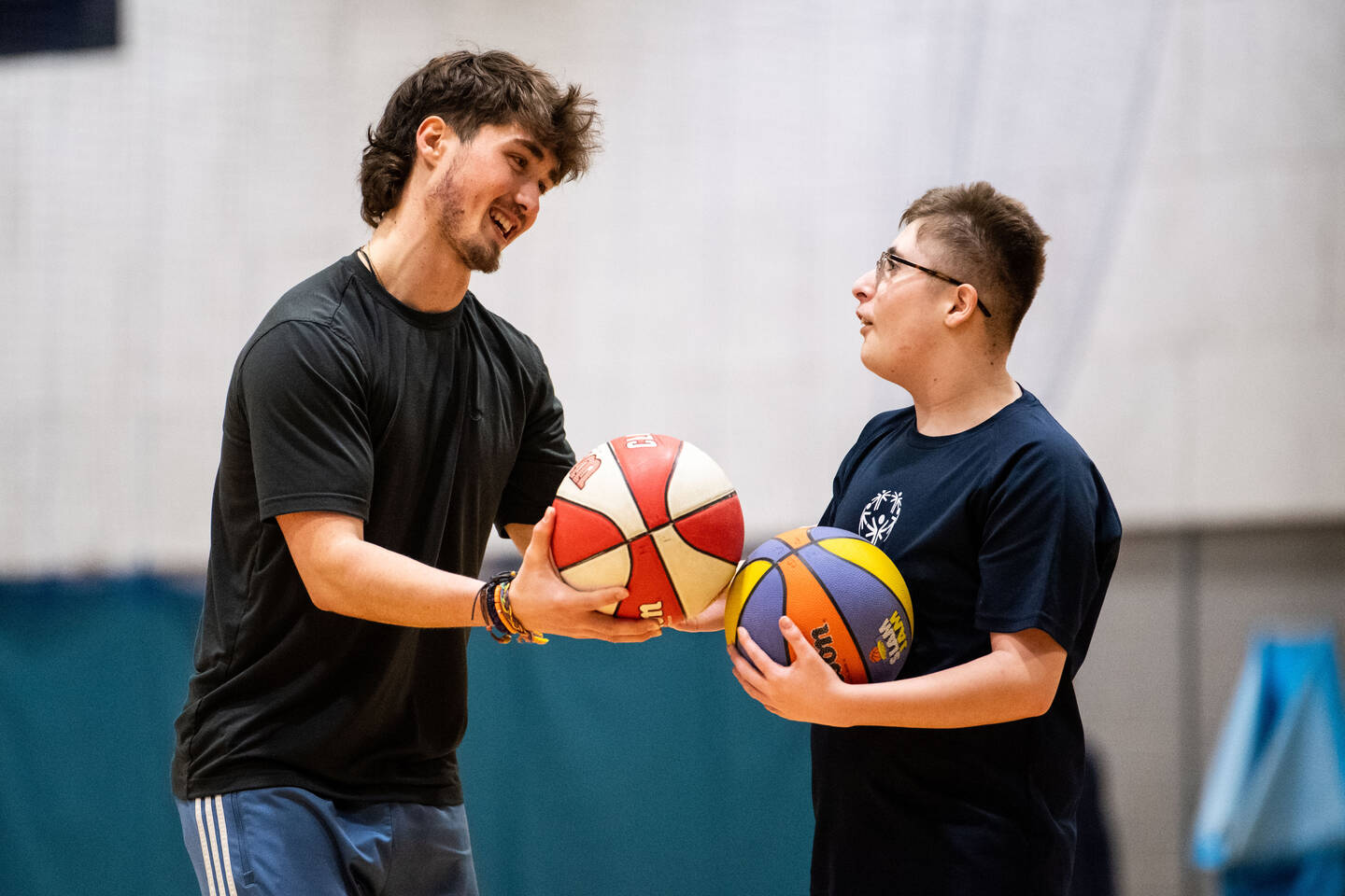 A coach hands a basketball to a young player.