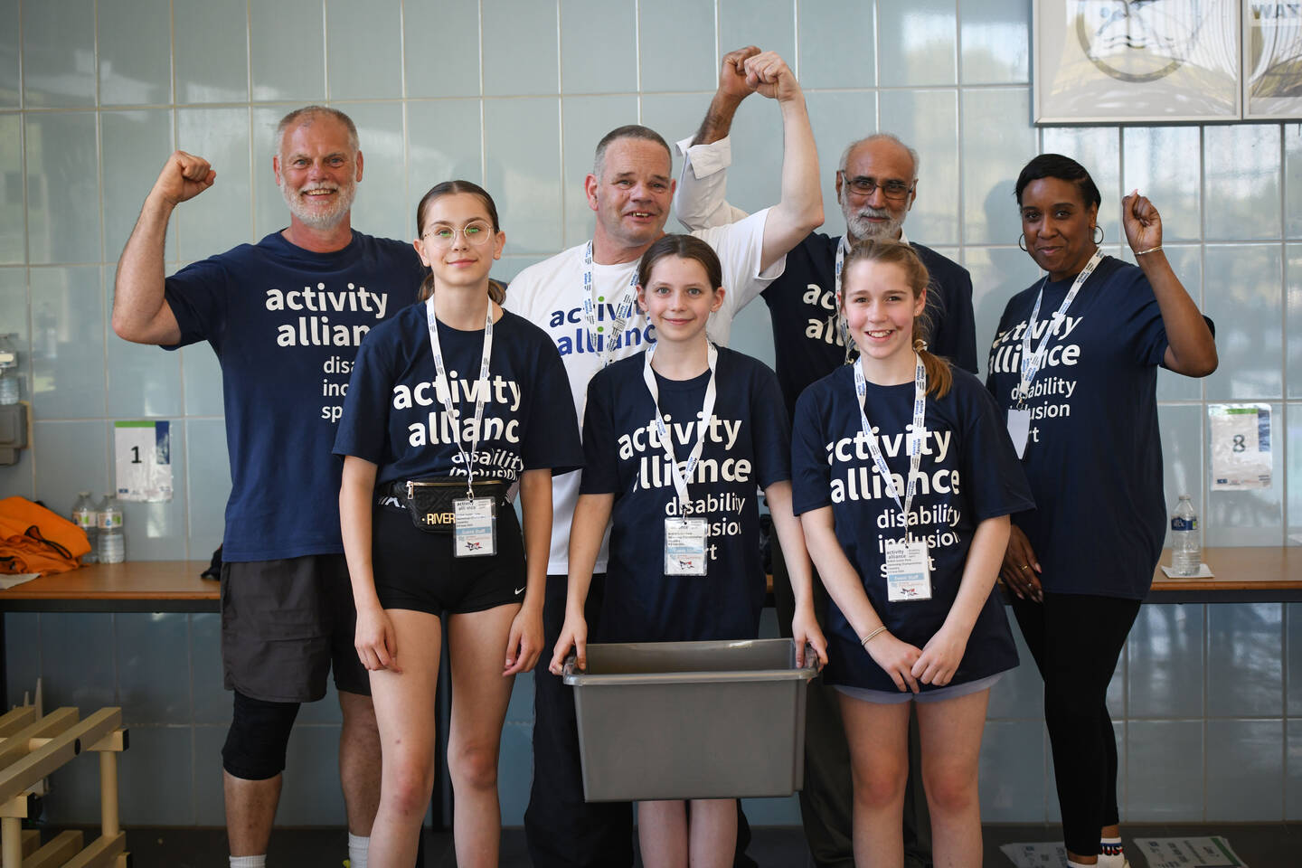 A group of volunteers smile beside a swimming pool.