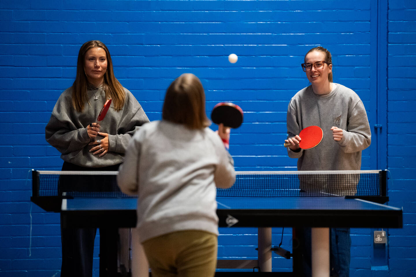 Three young people play table tennis