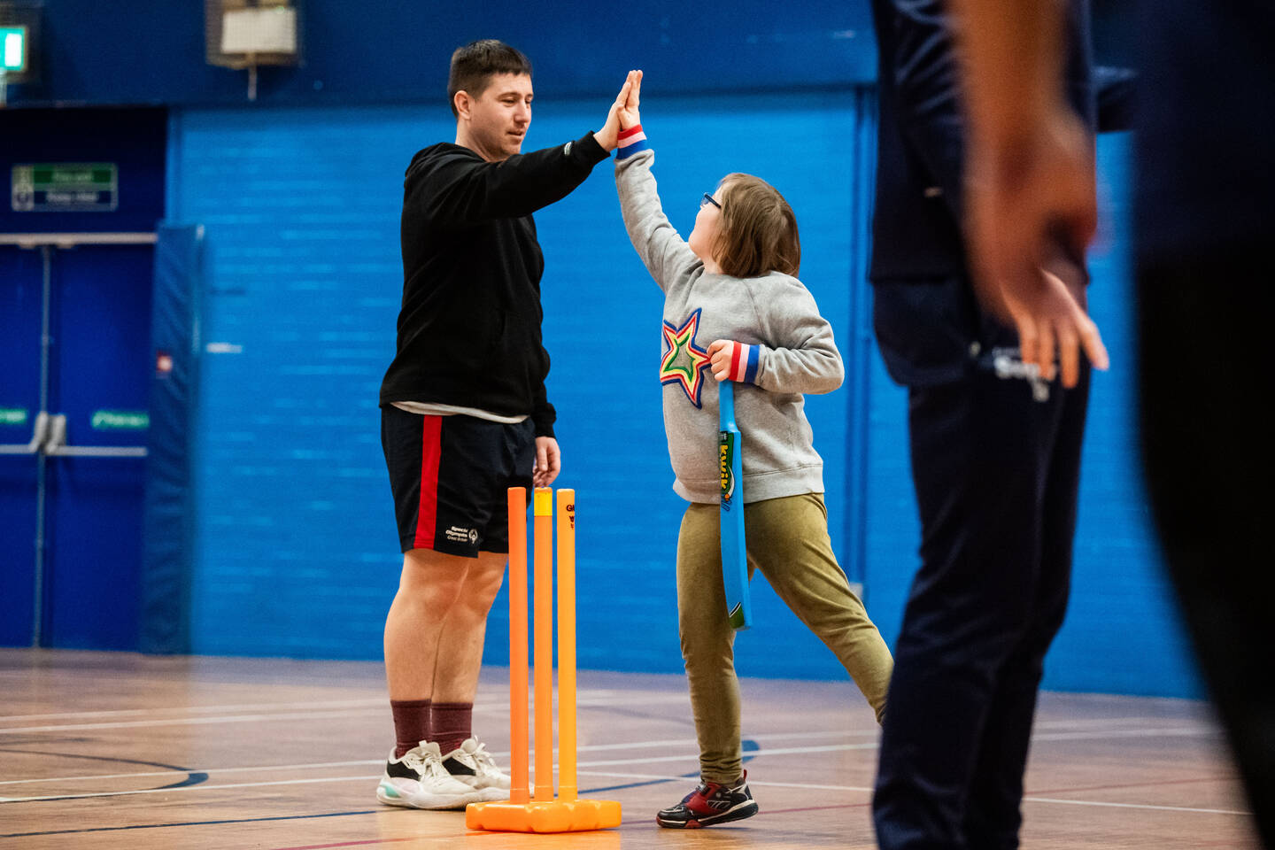A coach gives a high five to a girl playing cricket.