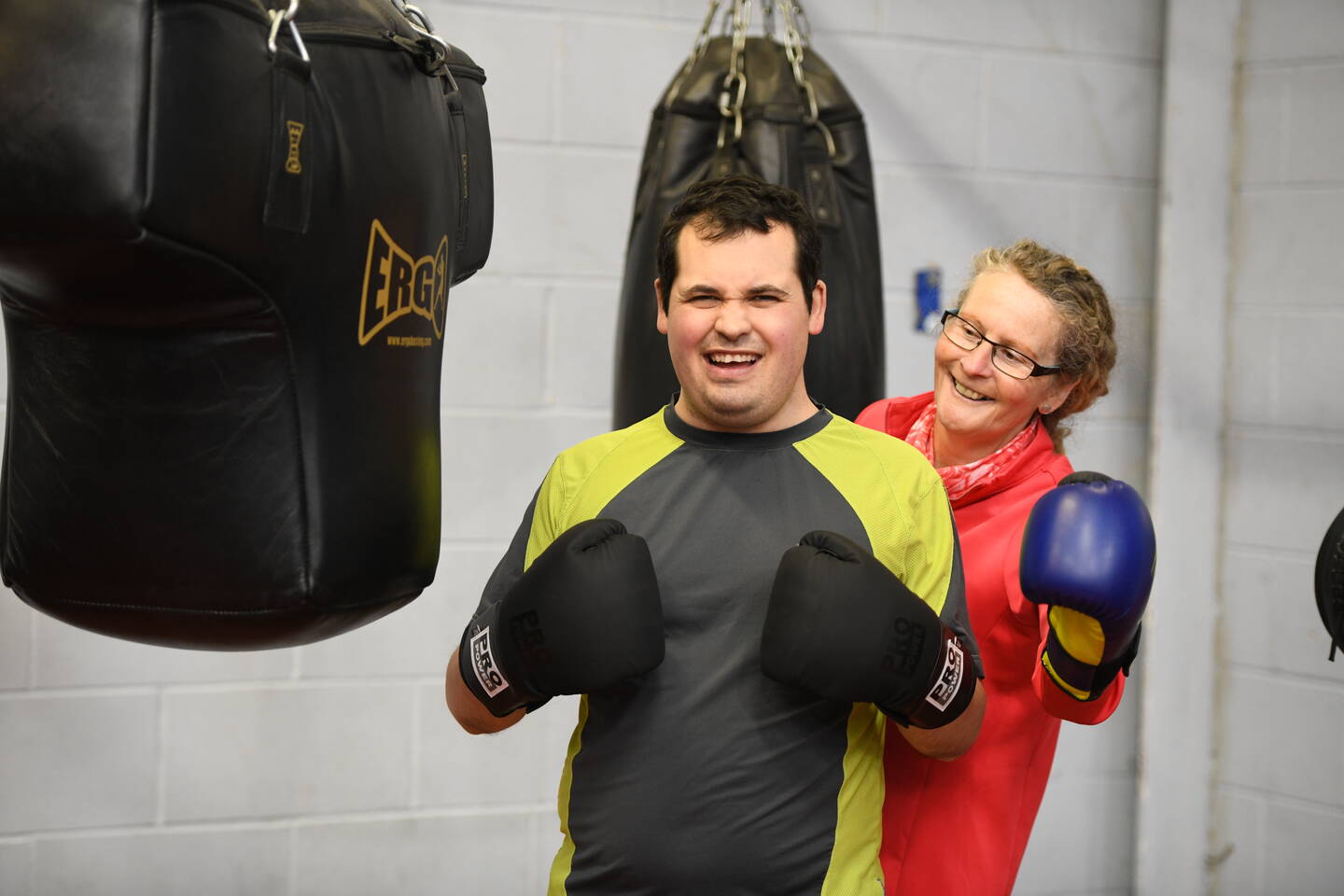 A man with boxing gloves on smiles next to a woman.