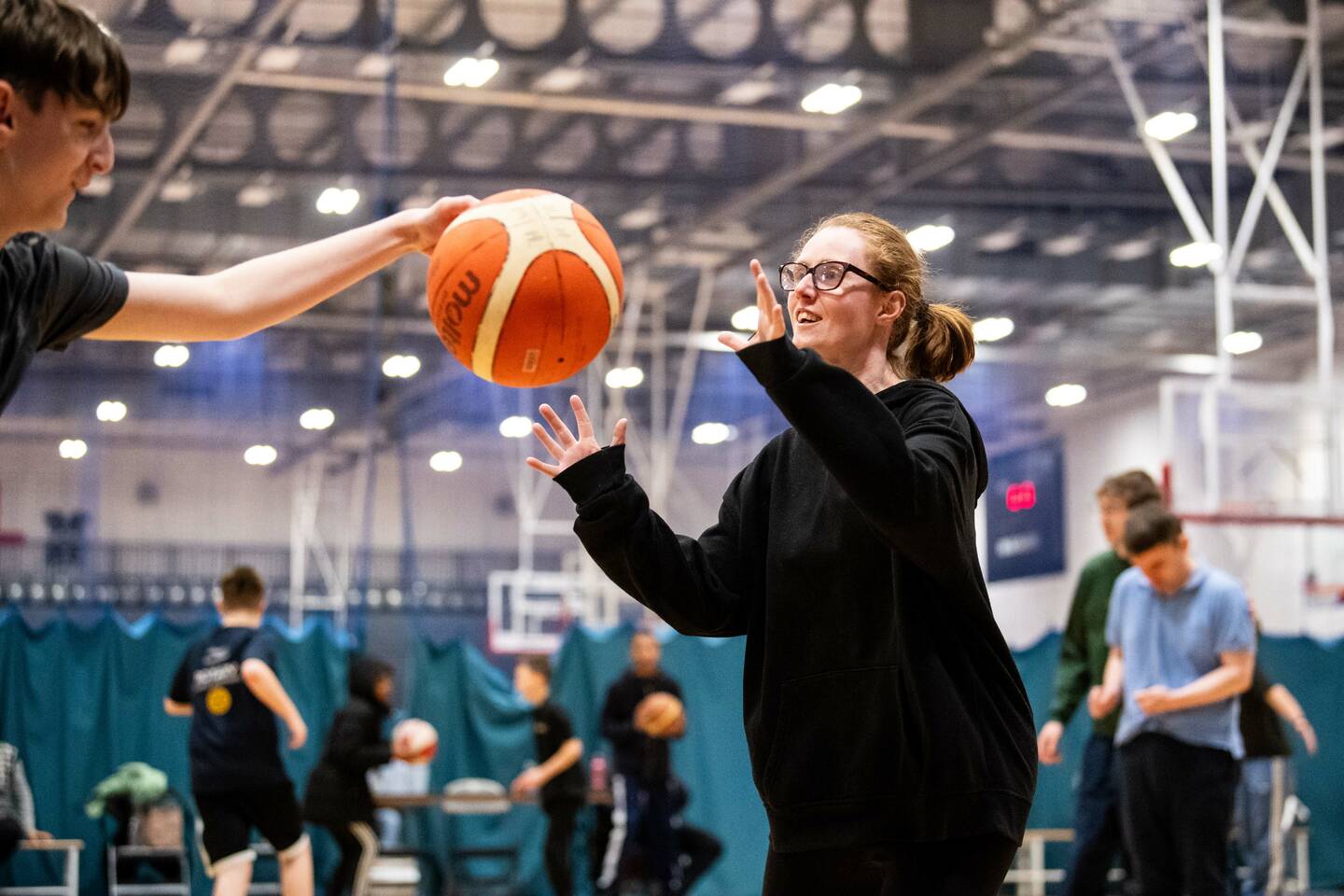 A woman catches a basketball being thrown at her.