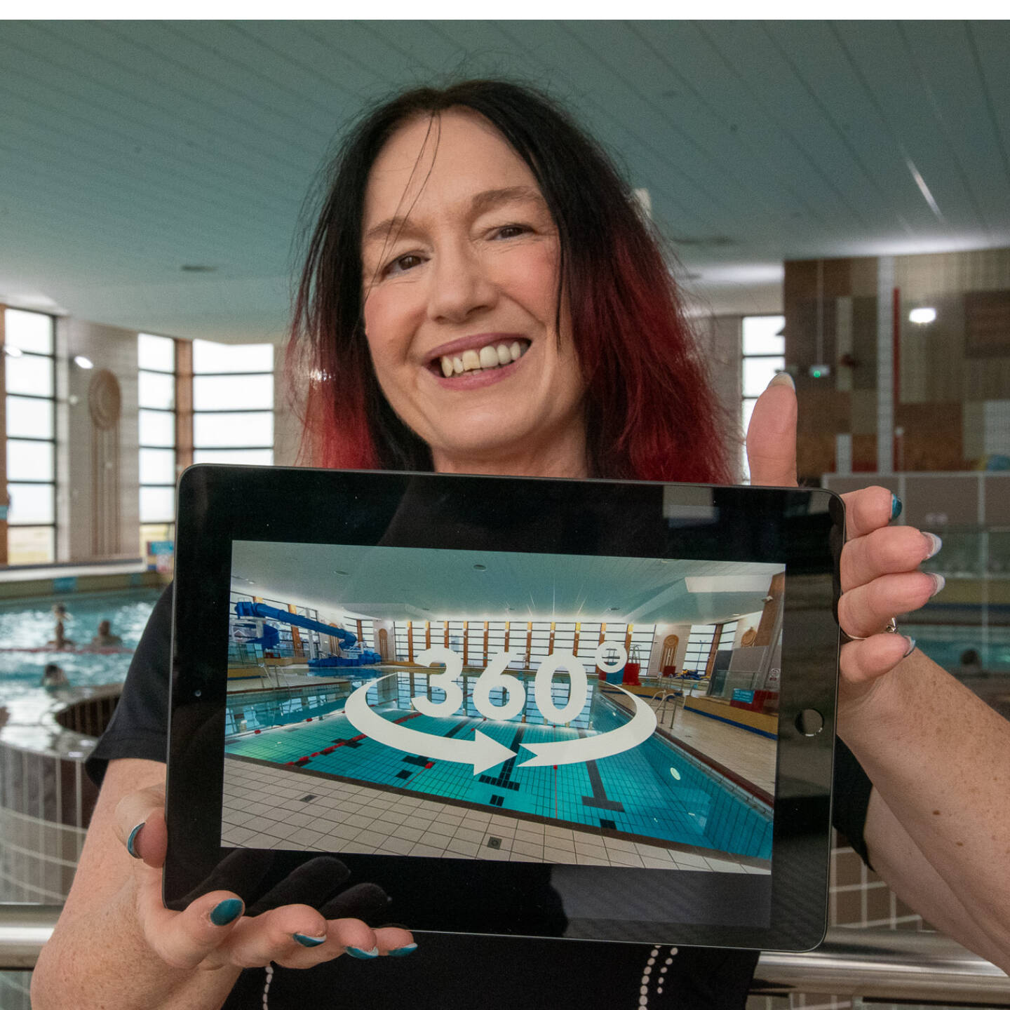 A woman stands in front of a swimming pool holding a tablet that shows an icon representing a 360 virtual tour.