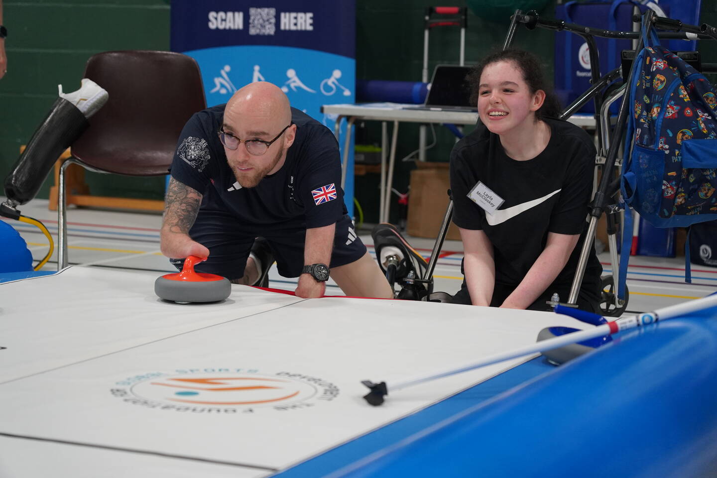 A man and a woman play floor curling.