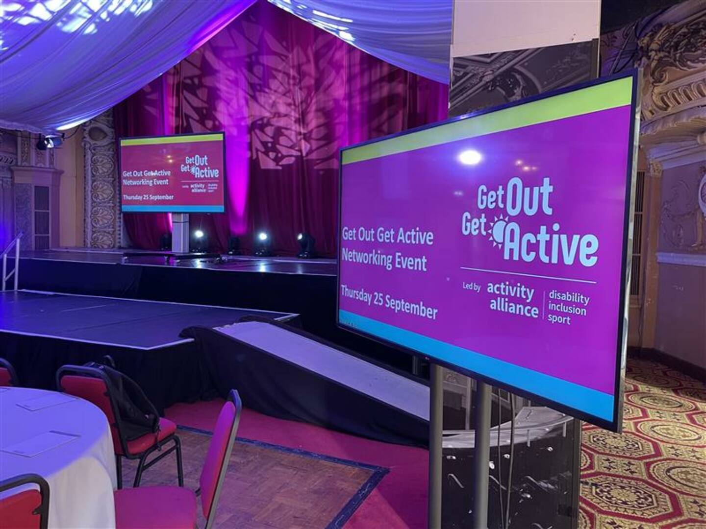 Two screens in an event space showing words that say GOGA Networking Event Blackpool.