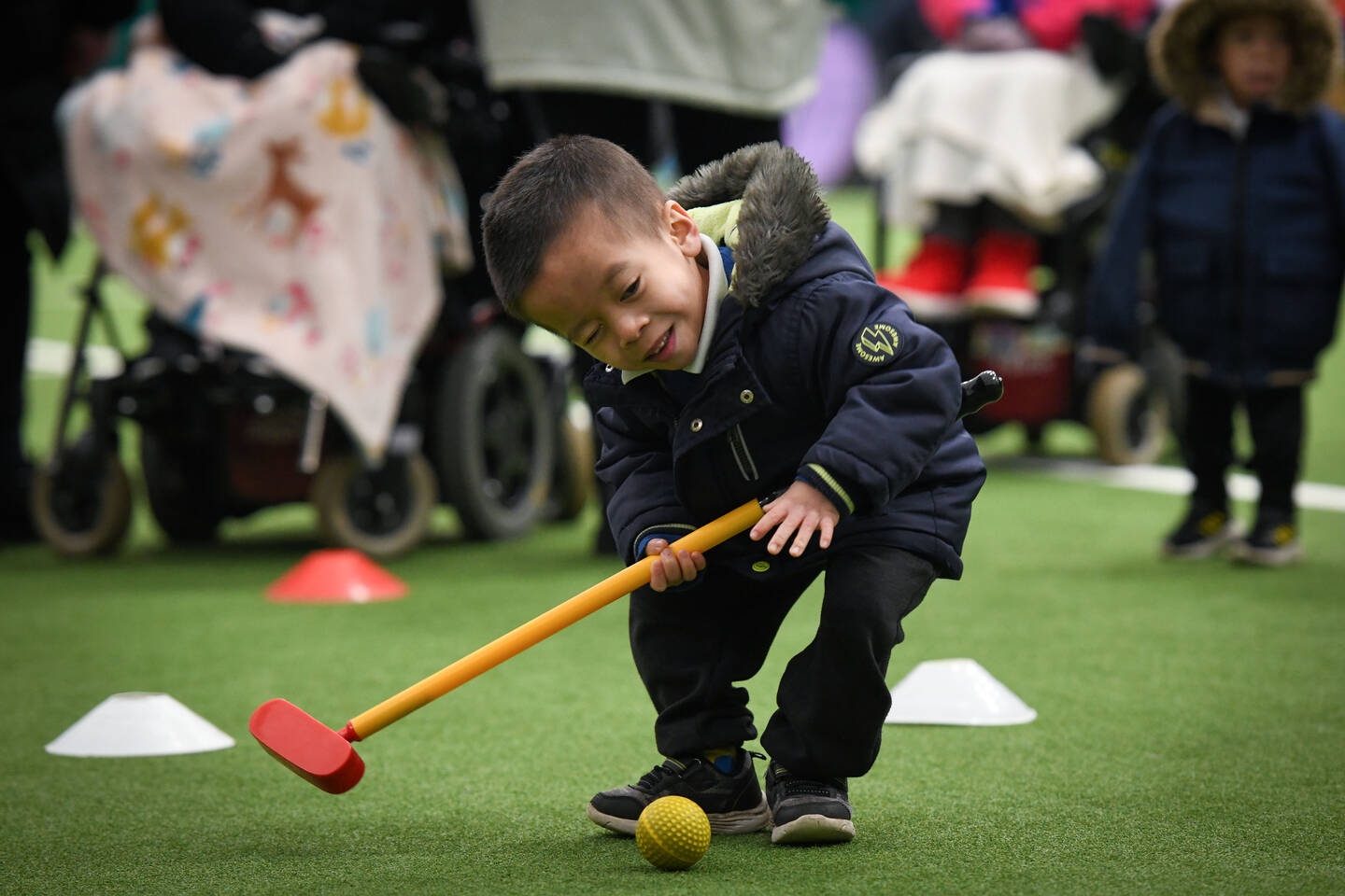 A young boy plays hockey in a sports hall.