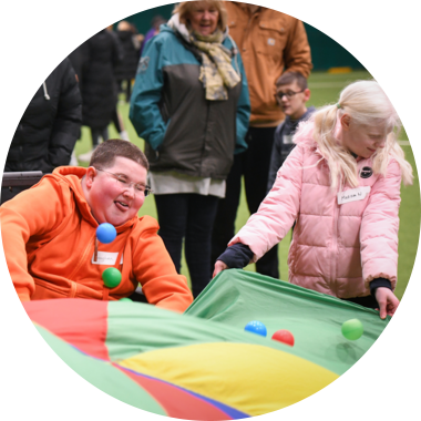 Young disabled boy playing with balls and parachute