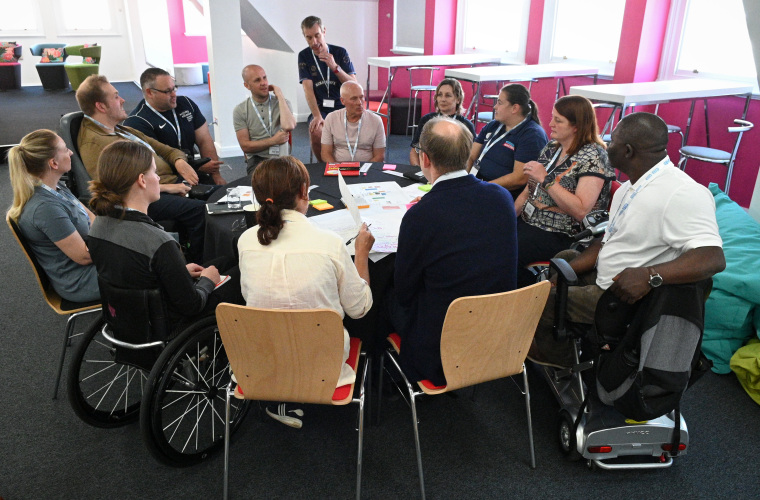 Group of disabled and non-disabled people having a discussion around a table at an Inlcude to Improve event