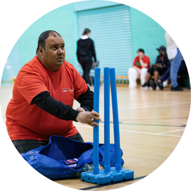 A disabled volunteer sets up plastic cricket stumps