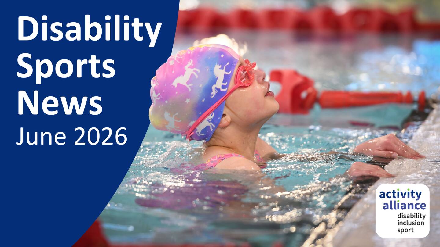 The image shows a young swimmer partially submerged in a swimming pool, with their head above the water. They are wearing a colourful swim cap and pink goggles. The individual is close to the edge of the pool, with both hands gripping the side. Red lane dividers are visible in the background