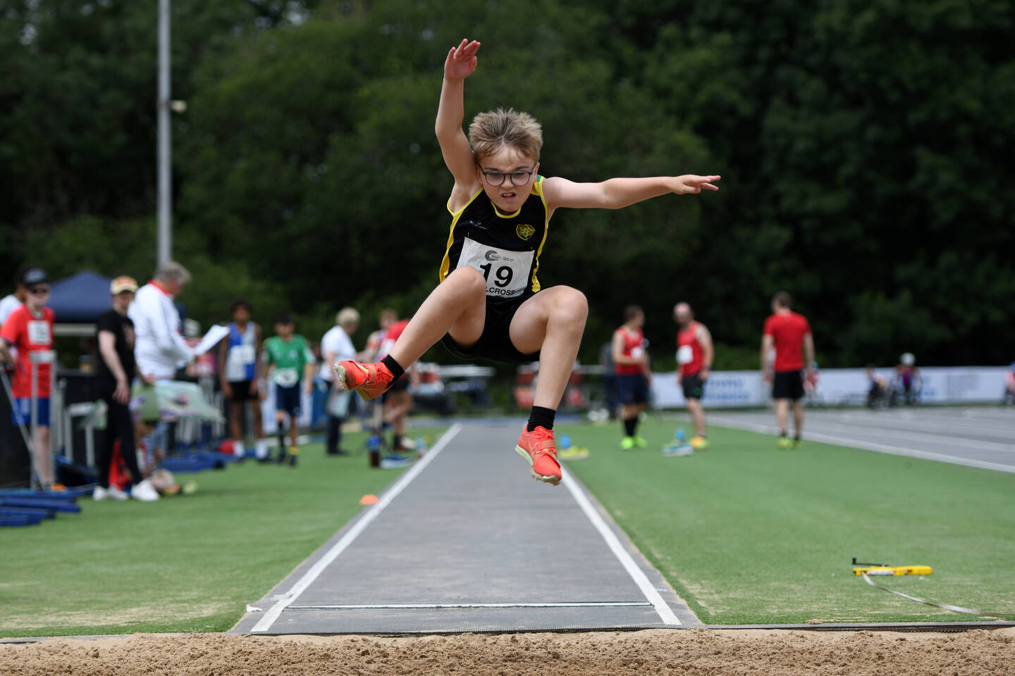 A young boy does the long jump into a sand pit at at the National Junior Para Athletics Championships.