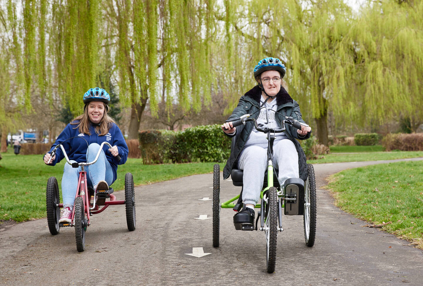 Two people on adapted cycles in the park