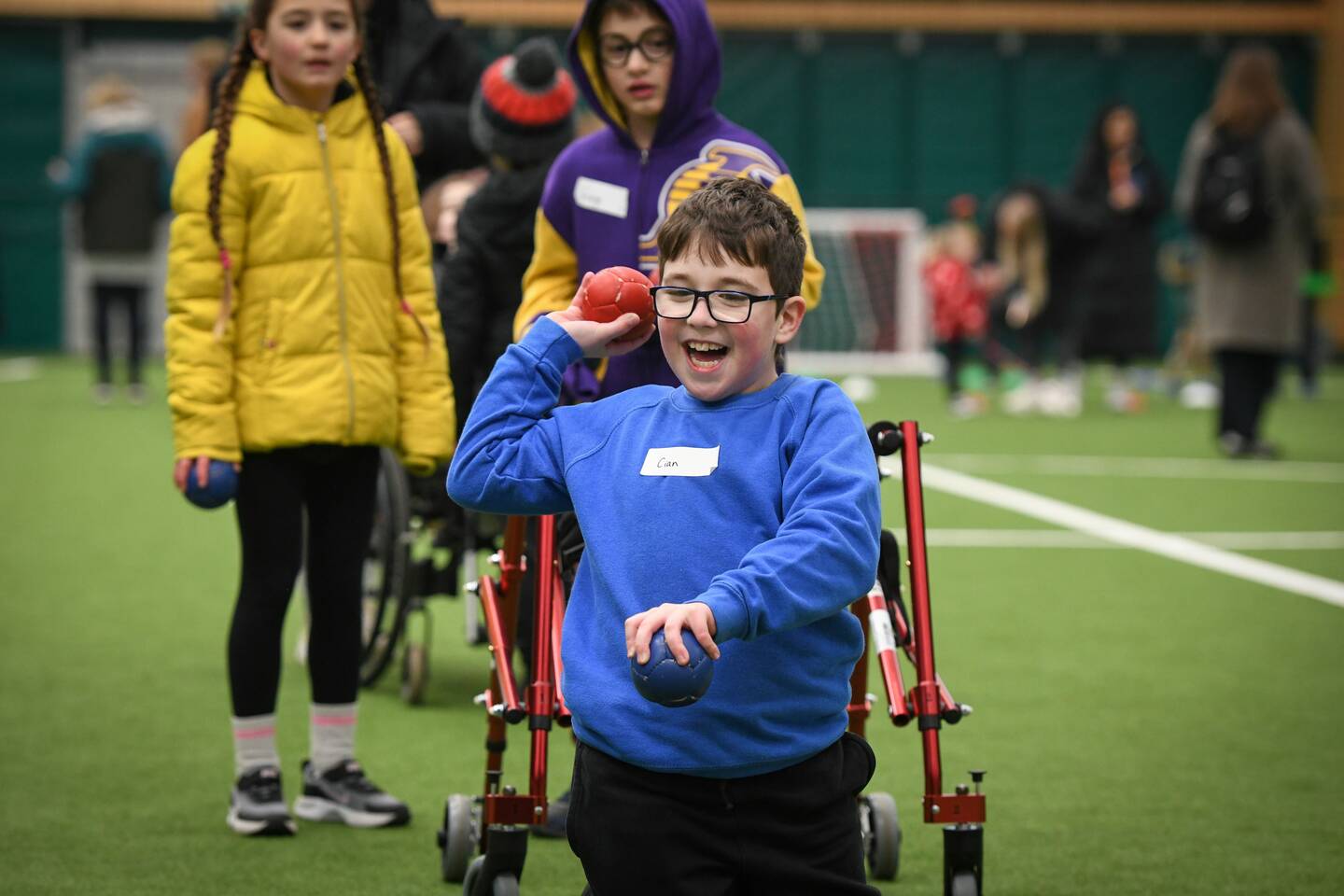 A young boy in a blue jumper throws a ball.