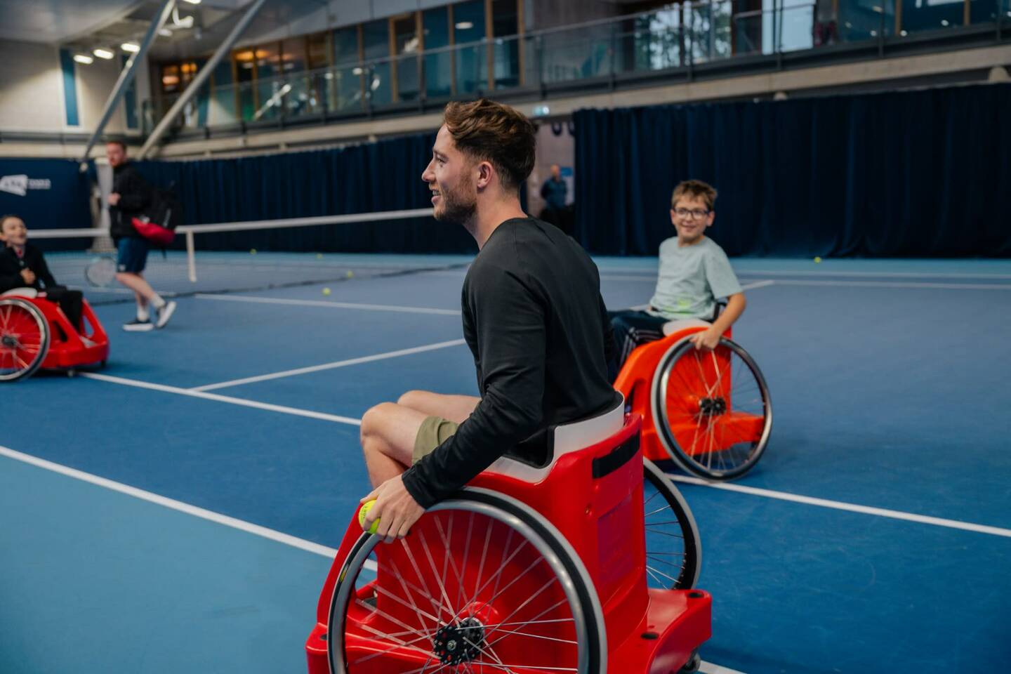 Alfie Hewett on a tennis court with a young tennis player. 