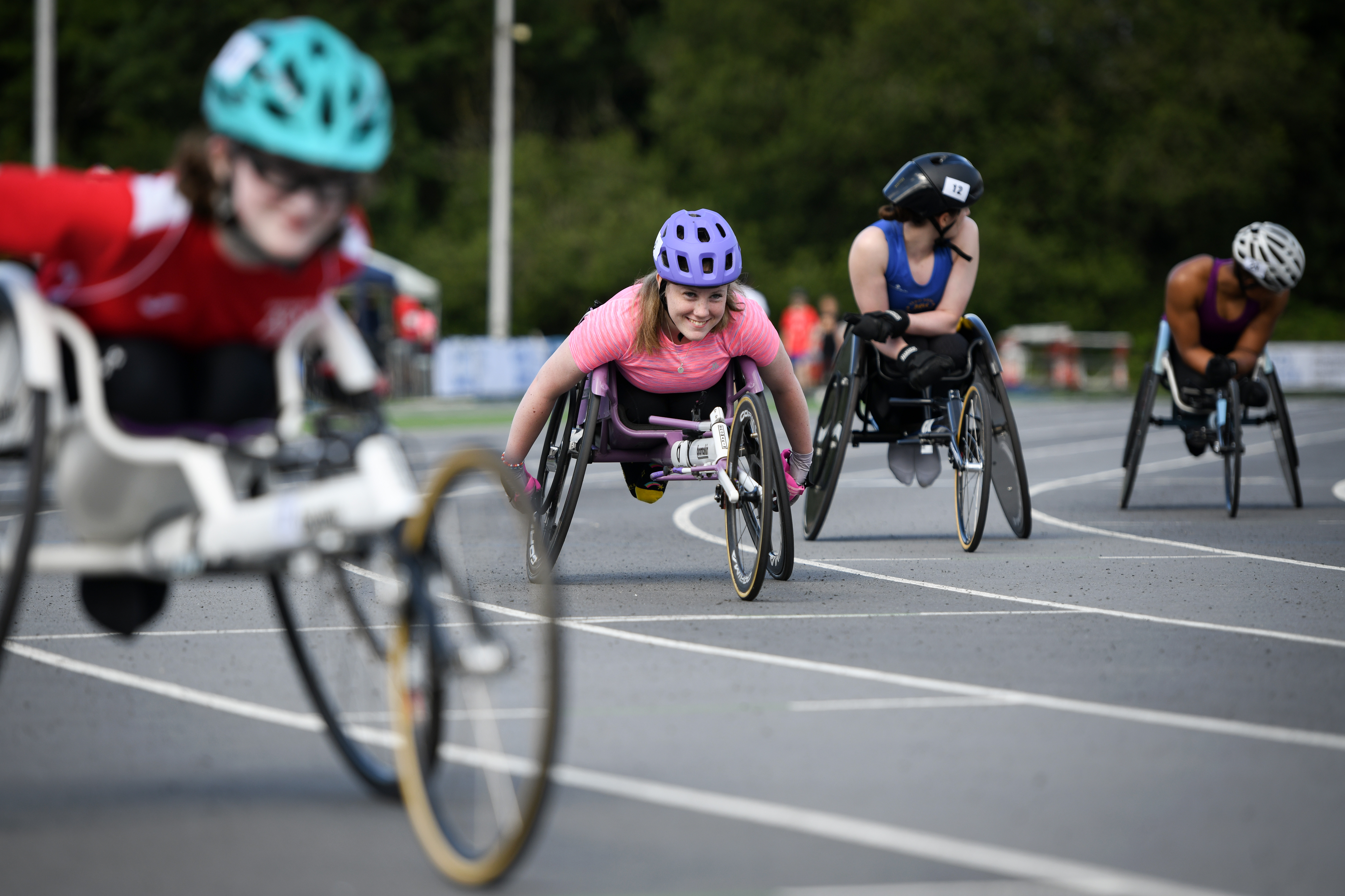 Four wheelchair racers line up on the tracks to race